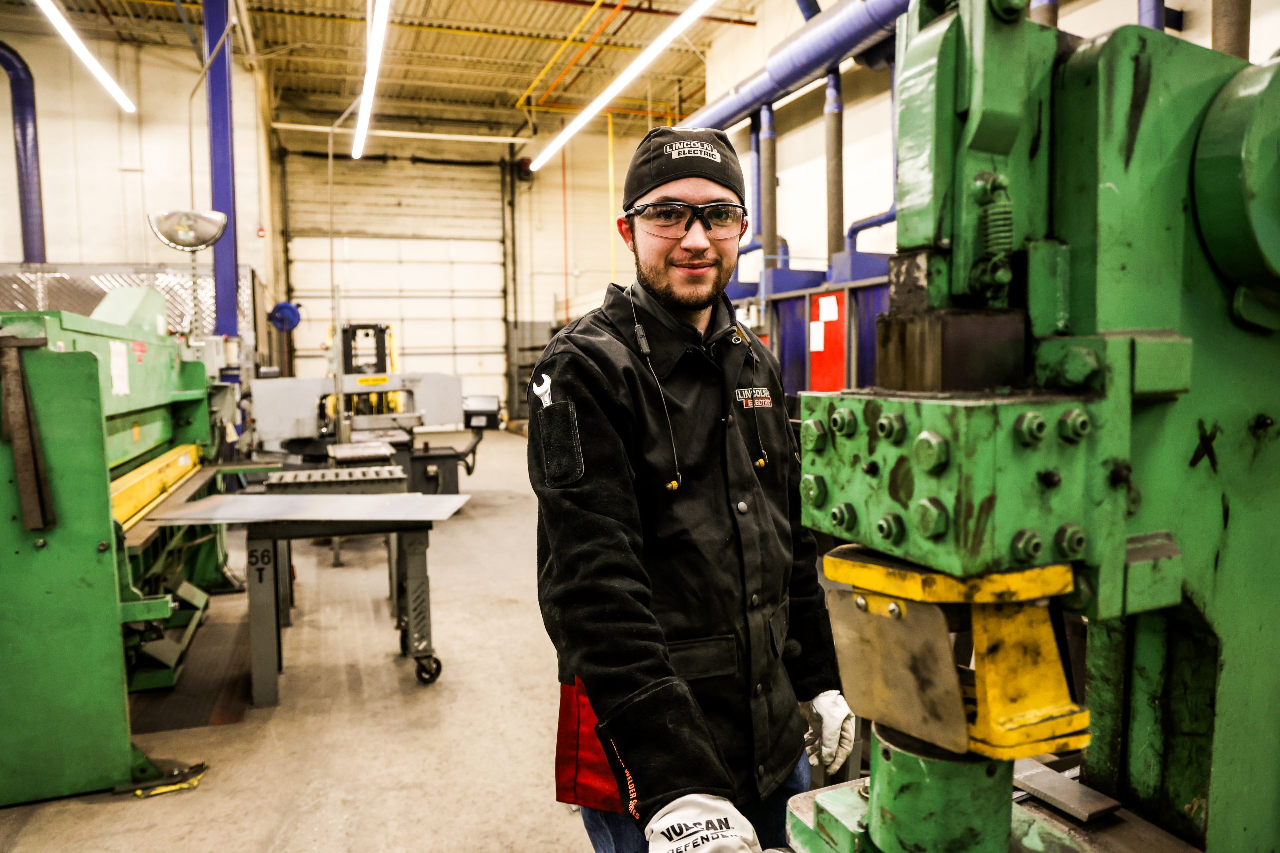 Student in OTECH's Welding Technology program smiling for a picture. Standing next to welding equipment.