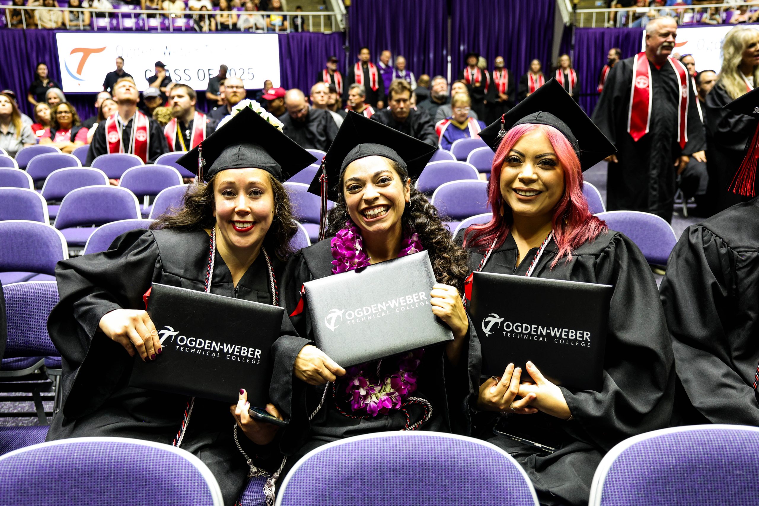 three graduates at ogden-weber technical college pose for a picture, holding their diplomas