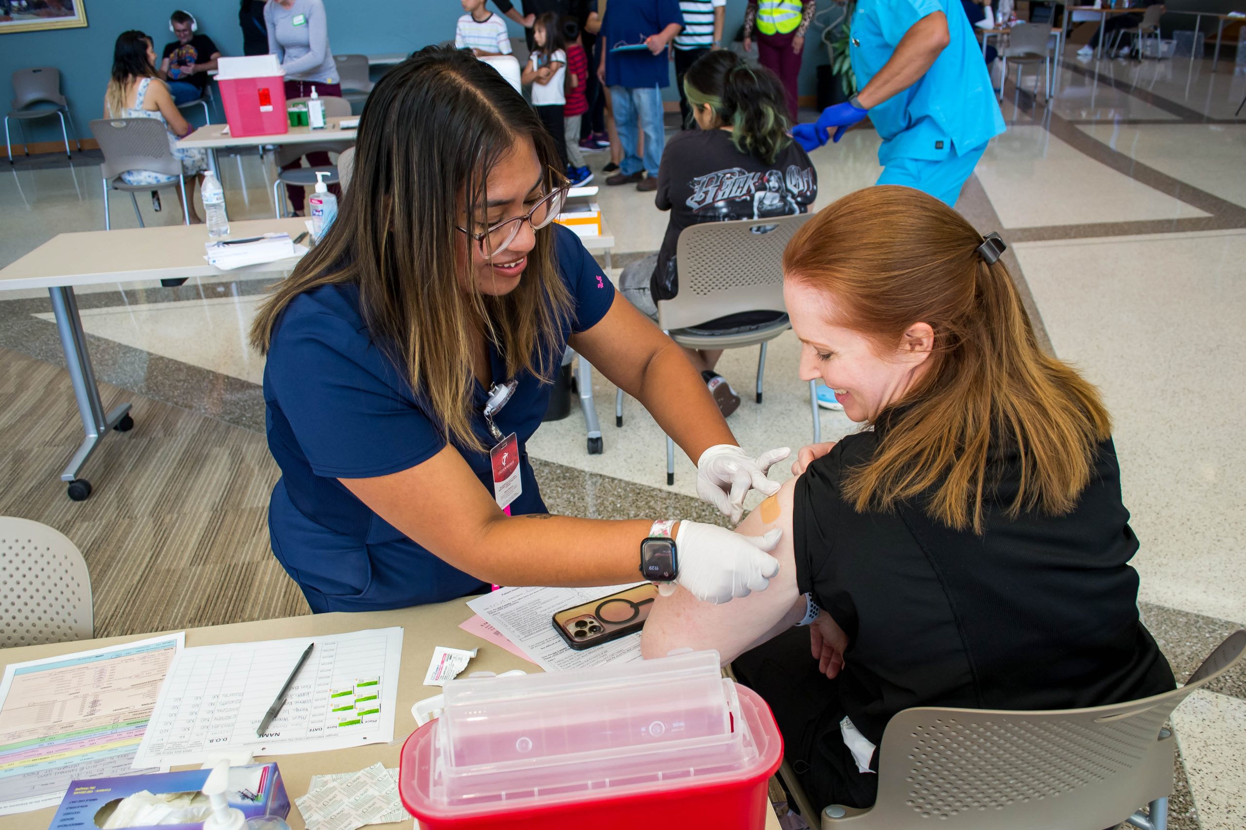 An Ogden-Weber Technical College healthcare student administers a vaccine to a seated community member during a free community health screening.