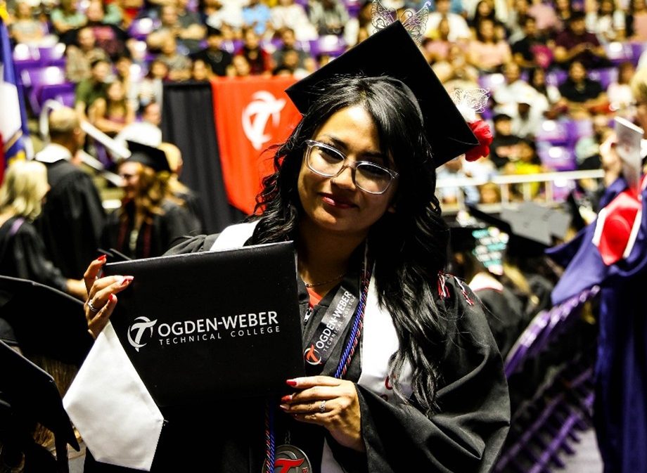 OTECH graduate holding their diploma during graduation ceremony.
