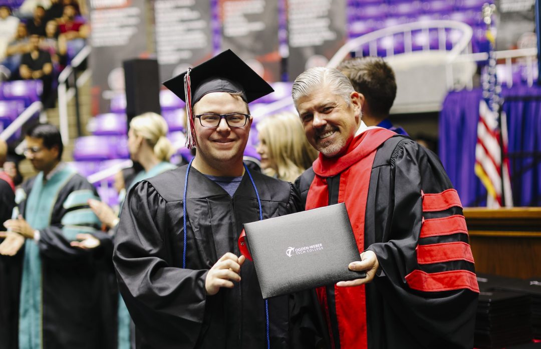 OTECH president hands a diploma to a student during the graduation ceremony.
